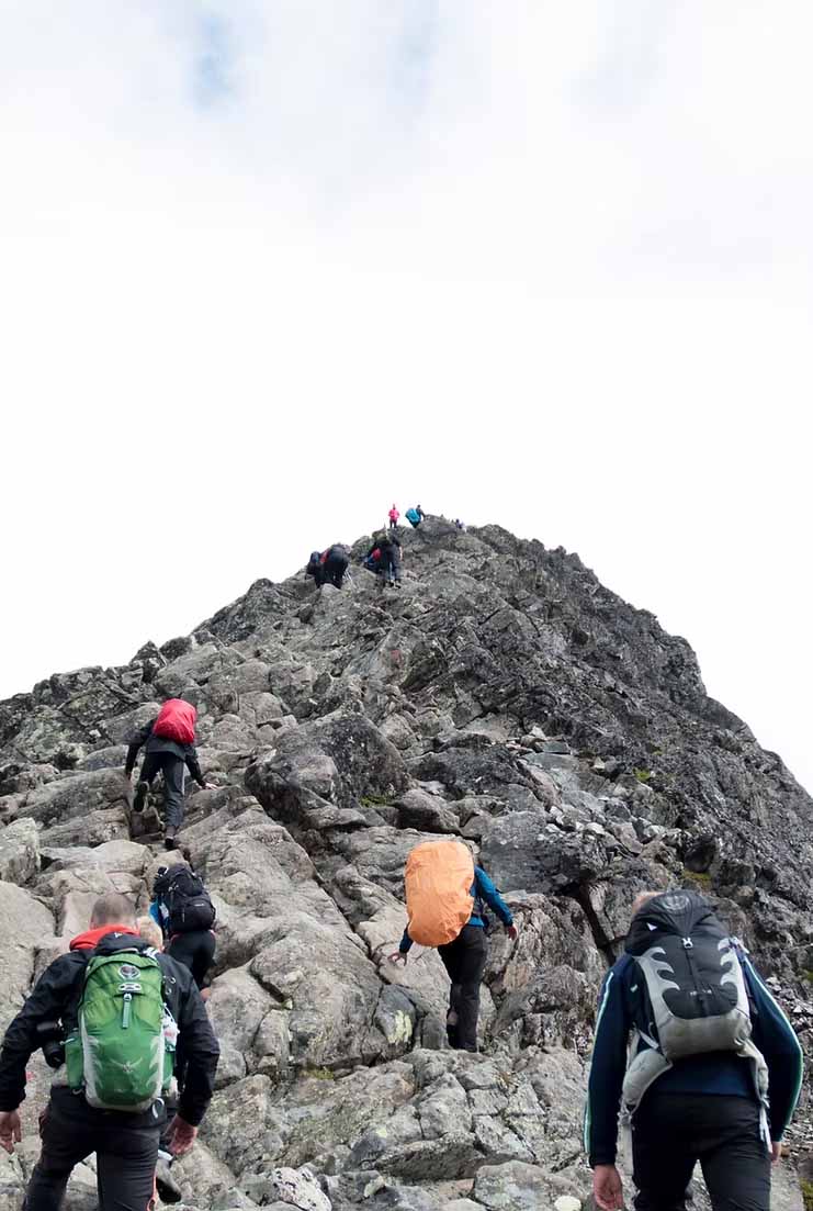 Team climbing rocky mountain peak, symbolizing the challenge of developing custom applications
